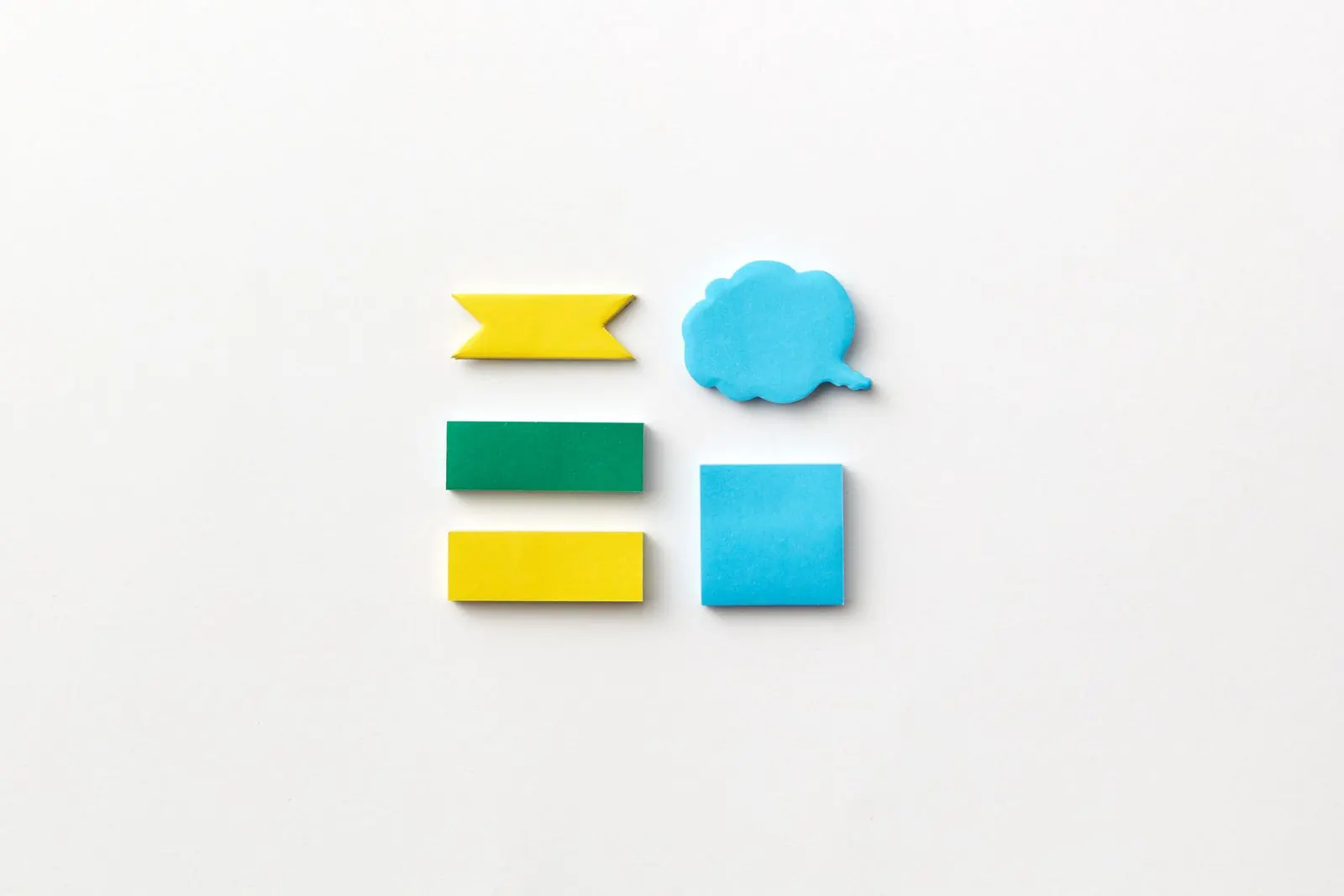 Colourful sticky notes cut into flags and speech bubbles on a white surface.