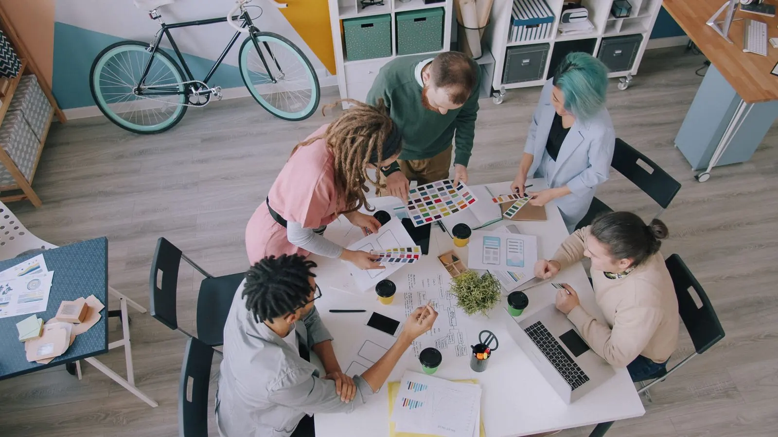 An overhead view of colleagues discussing colour samples around a creative worktable.