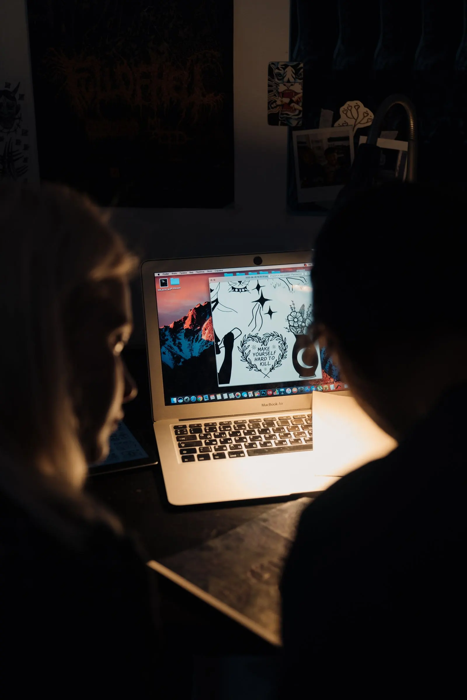 Two people look at artwork on a laptop in a warmly lit design space.