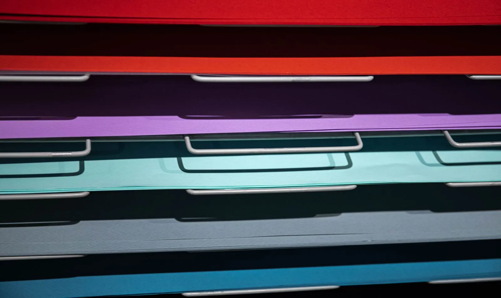 Overlapping cyan, purple and red paper folders form a striped arrangement.