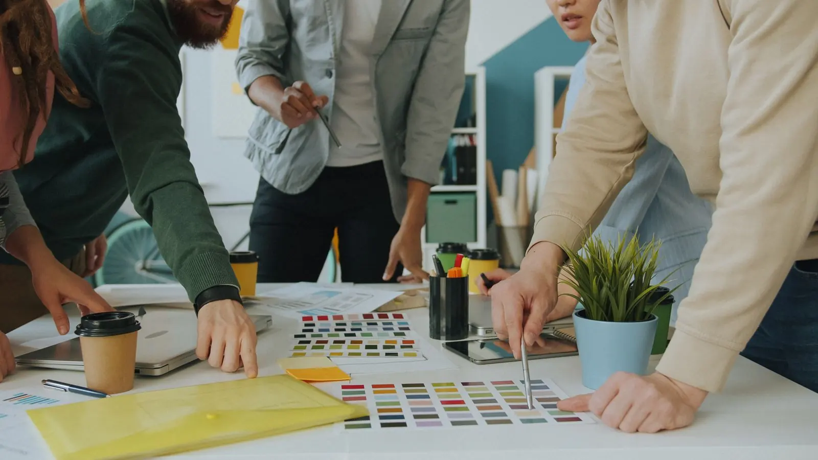Designers compare colourful material samples around a shared studio table.
